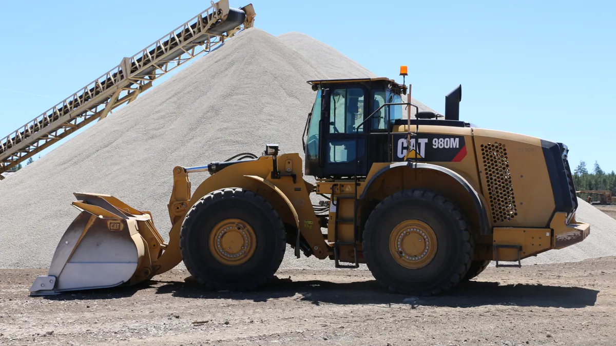 A Cat 980M wheel loader in front of a pumice stockpile and stacker conveyor at the Beaver Pumice operation